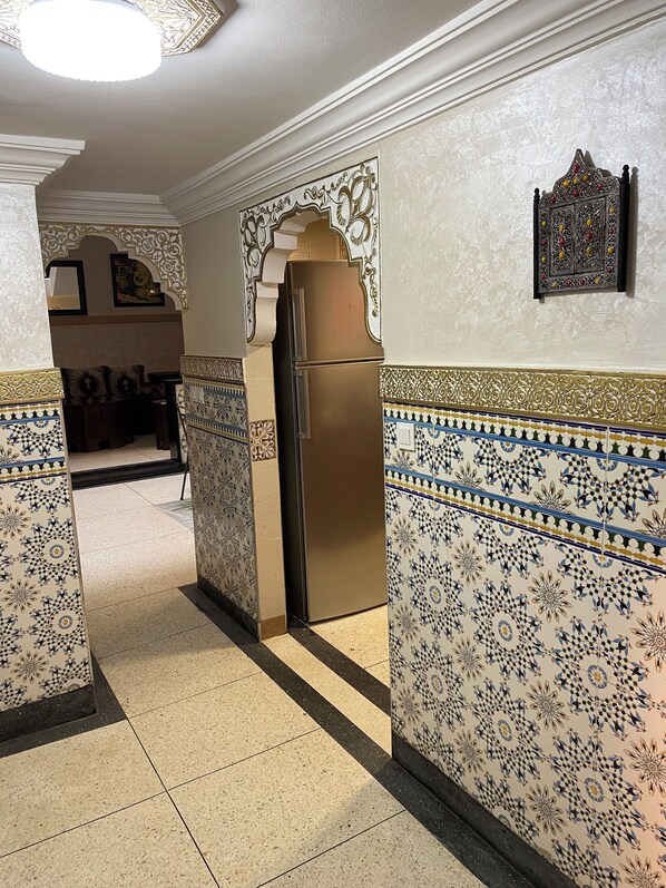 A hallway with patterned walls and a refrigerator.