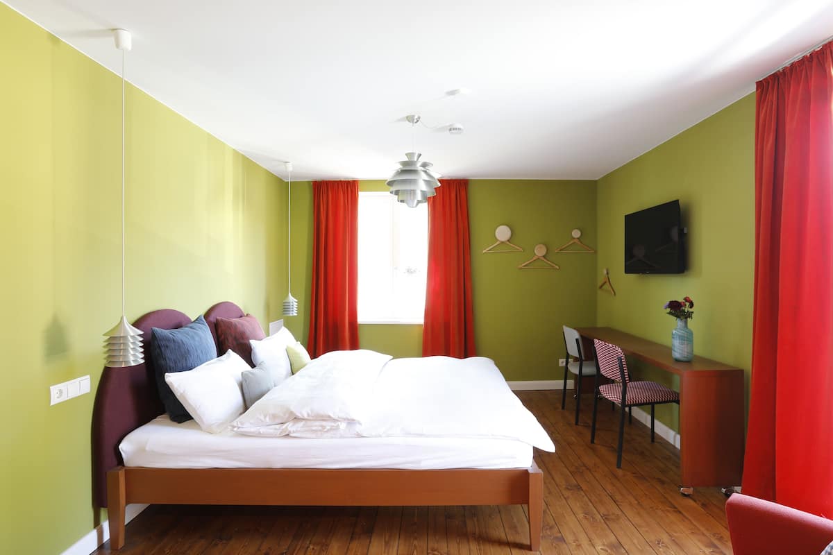 A bedroom with a bed, a desk, and a chair.