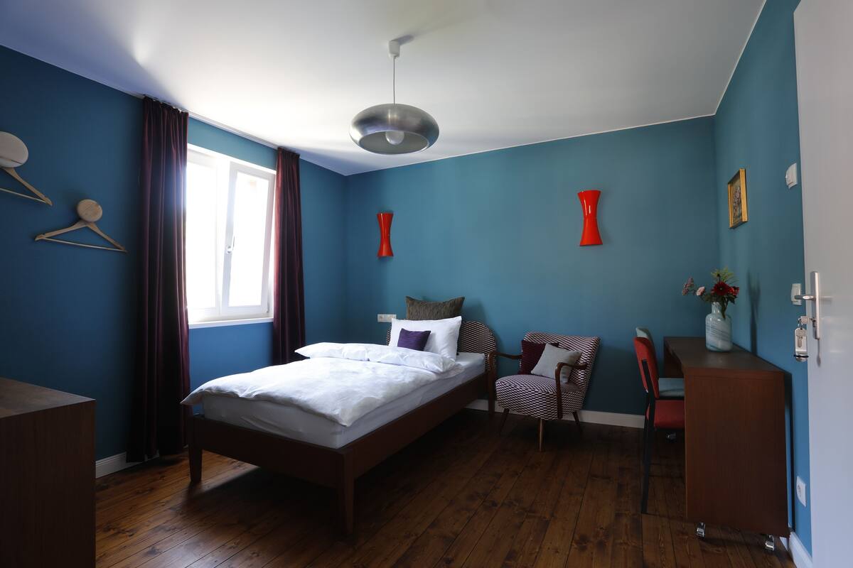 A bedroom with a bed, a desk, and a chair.
