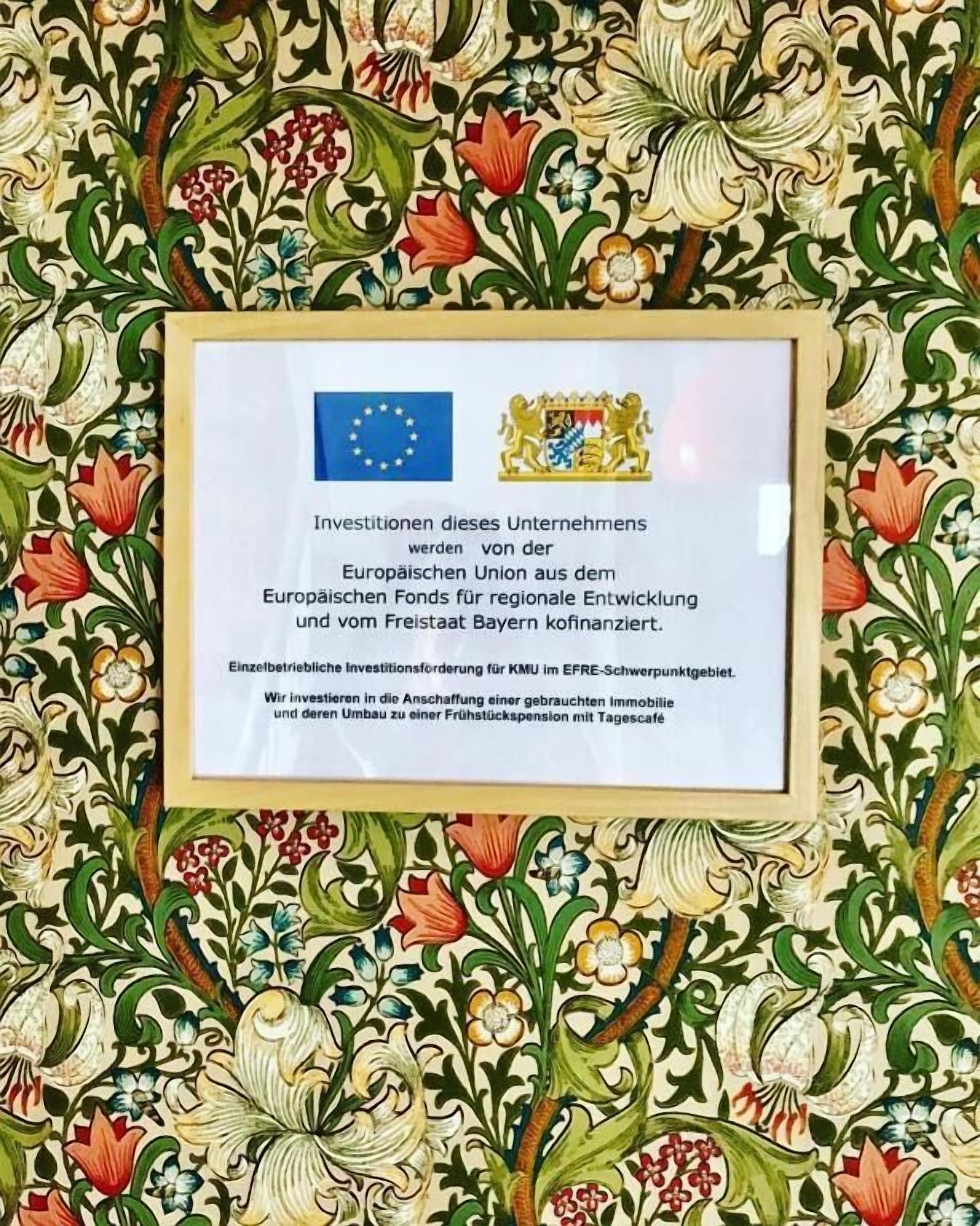 Un certificato incorniciato con la bandiera e lo stemma dell'Unione Europea, che attesta il sostegno agli investimenti per un'azienda nell'area EFRE-Swiftpointgebiet.