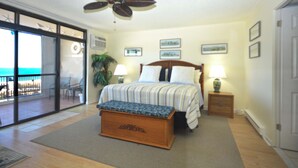 A bedroom with a bed, bedside tables, a ceiling fan, and a view through a sliding glass door to an outdoor area. - Exquisite, stylish 2 bedroom oceanfront condo great for families with free WiFi, an outdoor pool, and fabulous ocean view located uptown just steps to the beach! (Ocean City)