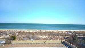 A beach view with a wooden deck and a fenced area. - Exquisite, stylish 2 bedroom oceanfront condo great for families with free WiFi, an outdoor pool, and fabulous ocean view located uptown just steps to the beach! (Ocean City)
