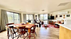 A spacious living area with a dining table, chairs, a sofa, and a TV. - A charming family-friendly retreat nestled in the tranquil heart of Venus Bay (Venus Bay)