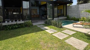Een modern huis met een grote glazen gevel, een zwembad en een verzorgd gazon.