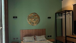 Een slaapkamer met een bed, een rond decoratief object aan de muur, een houten hoofdbord en een kledingrek.