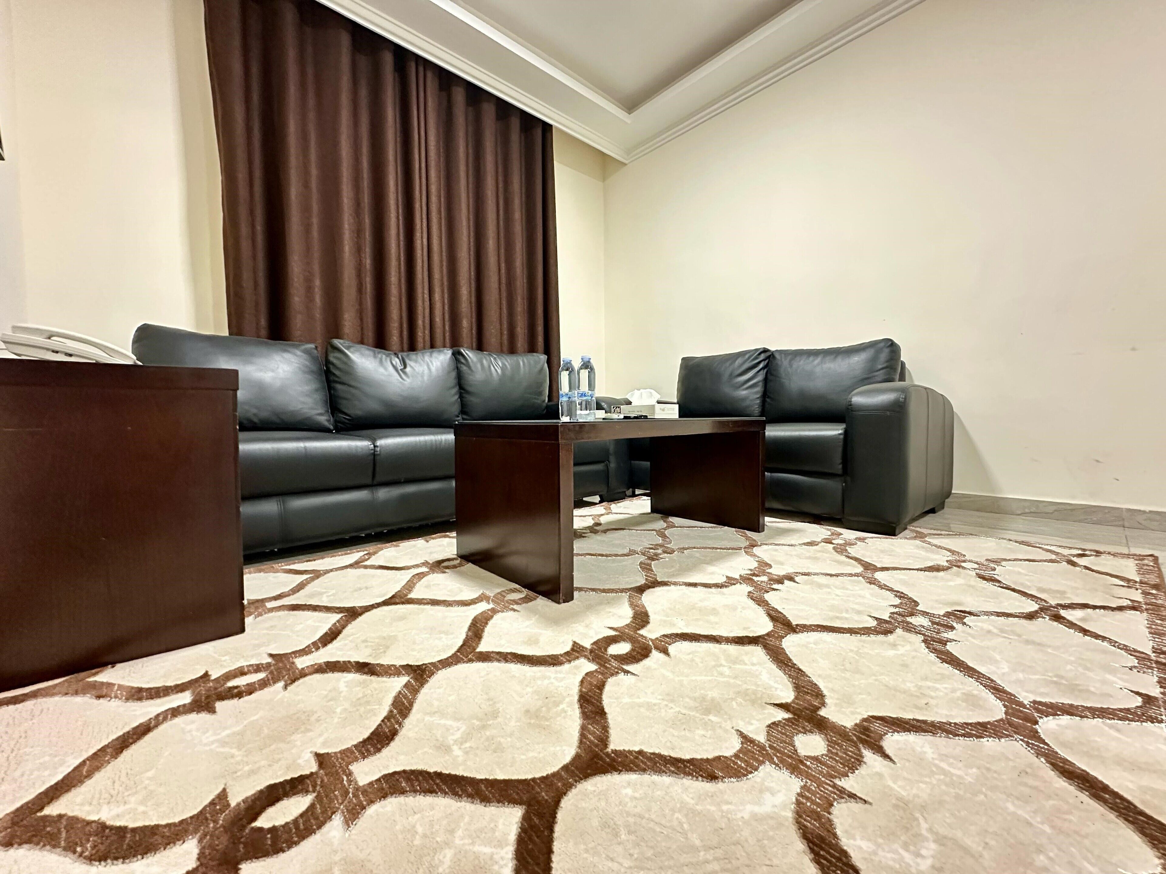 Ein Wohnzimmer mit einem dunkelbraunen Sofa, einem passenden Couchtisch und einem gemusterten Teppich.