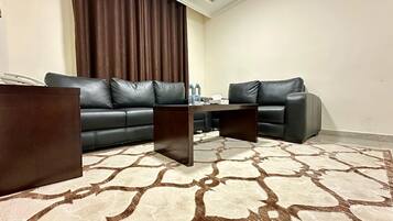 Ein Wohnzimmer mit einem dunkelbraunen Sofa, einem passenden Couchtisch und einem gemusterten Teppich.