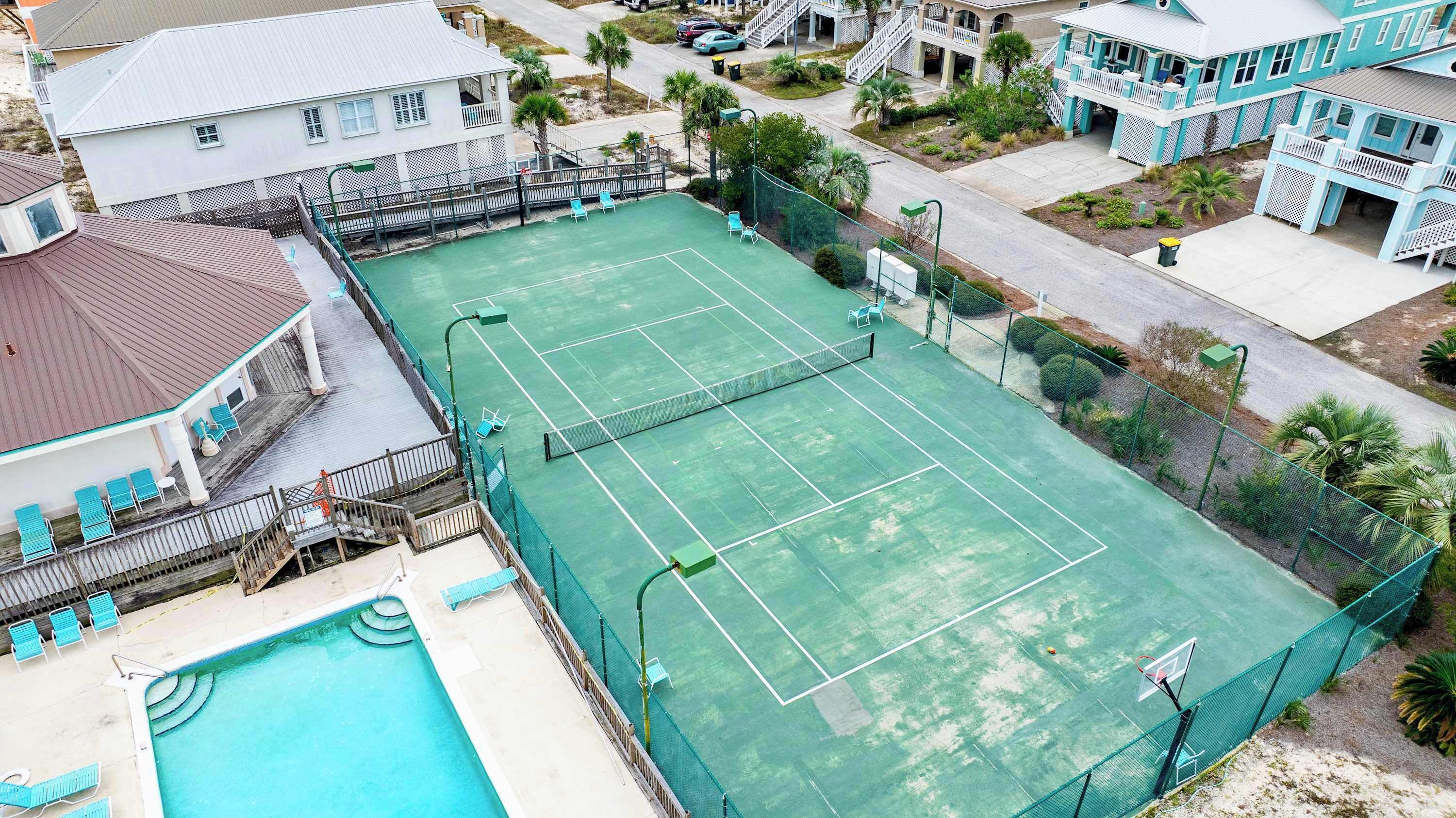 A tennis court with a pool and a building with a balcony.