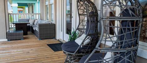 Un espacio al aire libre techado con sillas de mimbre, una mesa y un sofá.