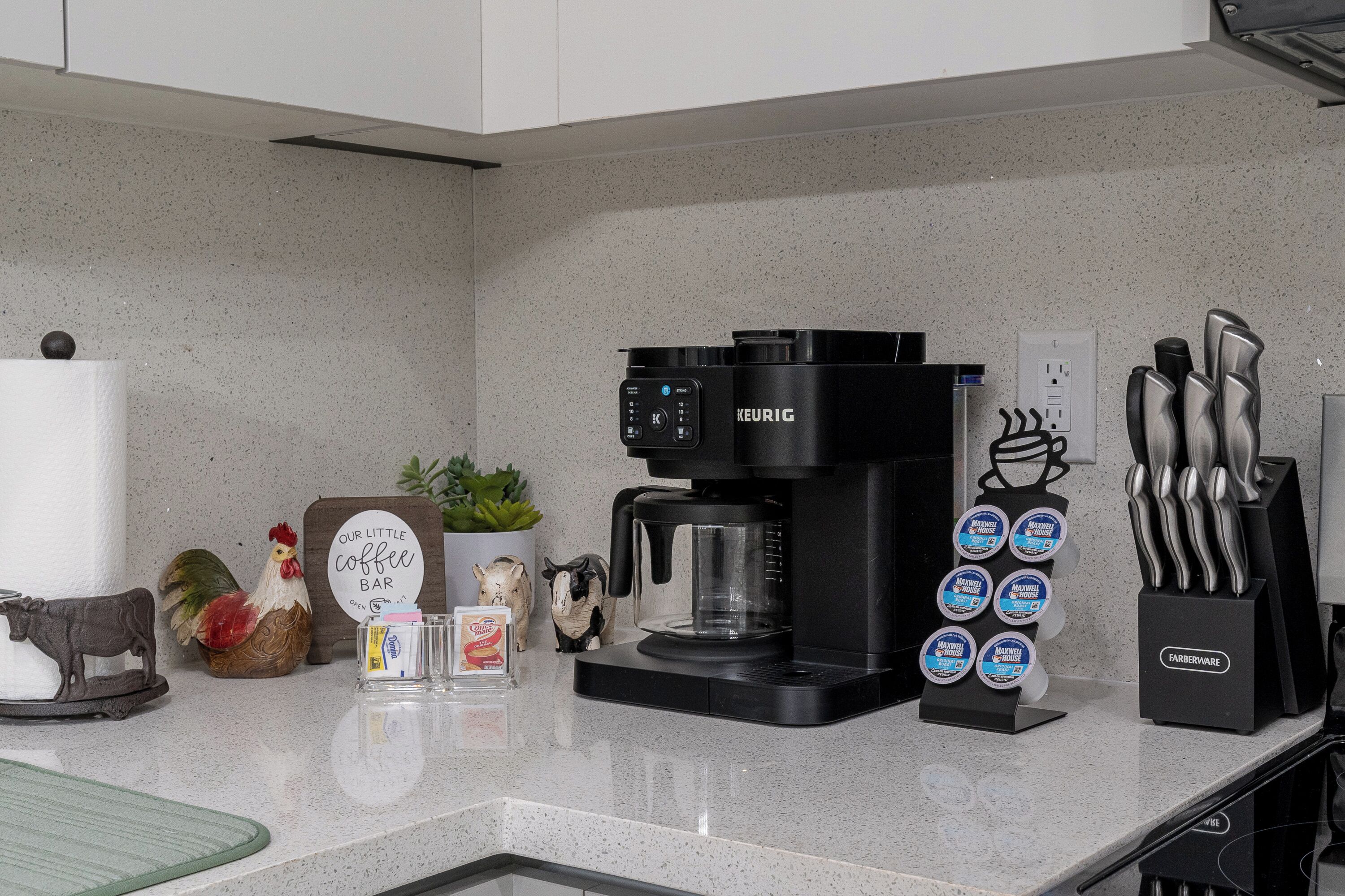 A kitchen counter with a Keurig coffee maker, a Farberware knife block, and various kitchen utensils.