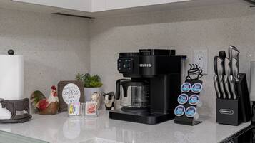A kitchen counter with a Keurig coffee maker, a Farberware knife block, and various kitchen utensils.