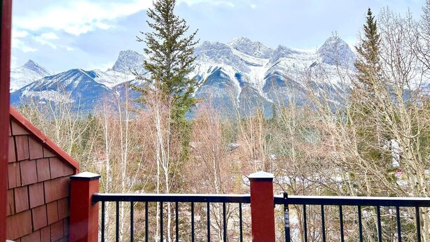 Une vue sur la montagne depuis un balcon doté d’une balustrade en bois et d’un mur rouge.