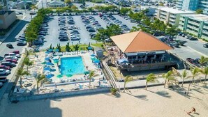 Un hôtel situé en bord de mer, doté d’une piscine, de chaises longues et de parasols.