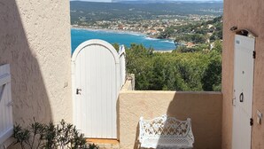 A balcony with a white door, a white bench, and a view of a coastal town and ocean. - T3-LES TERRASSES DE LA MADRAGUE-SEA VIEW-PARKING LOT (Saint-Cyr-sur-Mer)