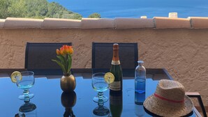 A table with a bottle of champagne, a glass with a lemon slice, a vase with flowers, and a straw hat. - T3-LES TERRASSES DE LA MADRAGUE-SEA VIEW-PARKING LOT (Saint-Cyr-sur-Mer)