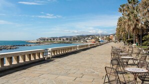 A coastal walkway with stone paving, outdoor seating, and a view of the sea and distant buildings. - 2 bedroom cozy apartment in Sanremo (Sanremo)