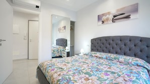 A bedroom with a large bed, a mirror, a bedside table, and a wall-mounted artwork. - 2 bedroom cozy apartment in Sanremo (Sanremo)