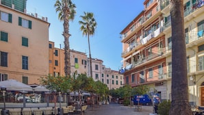 A pedestrian street with outdoor seating, palm trees, and multi-story buildings with balconies. - 2 bedroom cozy apartment in Sanremo (Sanremo)