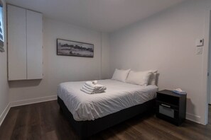 Ein Schlafzimmer mit einem Bett, einem Nachttisch, einem Bild an der Wand und einem Kleiderschrank.