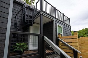 A two-story building with a wooden deck, a spiral staircase, and a fenced area with plants. - Salt & Pepper ("In The Pines" at KY Lake) | 121 & 131 Pine Grove Lane, Dover, TN 37058 (Dover)