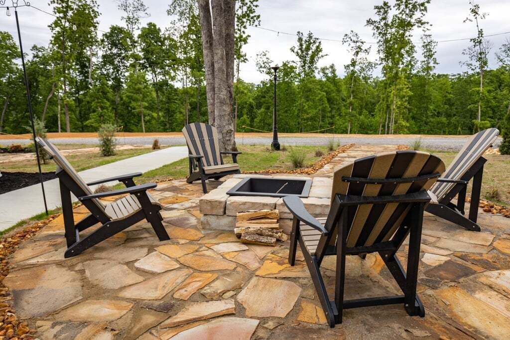A stone patio with Adirondack chairs and a fire pit.