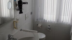 Ein modernes Badezimmer mit Waschbecken, Toilette und einem an der Wand befestigten Föhn.