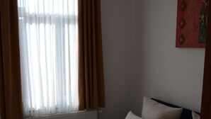Ein Hotelzimmer mit zwei Betten, einem Heizkörper und einem Vorhangfenster.