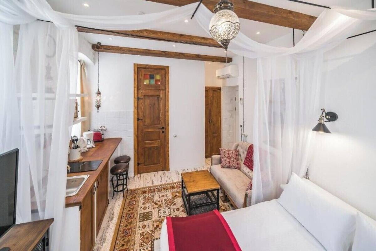 Une pièce compacte comprenant un coin cuisine, un canapé, un lit et un tapis à motifs.