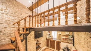 Ein rustikales Interieur mit einer Holztreppe, Steinwänden, einer Küchenzeile und einer gemütlichen Sitzecke.
