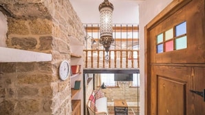 Ein rustikales Interieur mit freiliegenden Steinwänden, einer Holztür und einer hängenden Laterne.