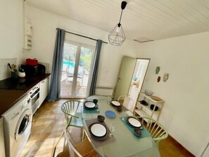 Enjoy meals in the dining area with a glass-top table for four, featuring plates and cutlery.