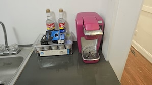 Een keuken met een spoelbak, een koffiezetapparaat en verpakkingen koffiecups.