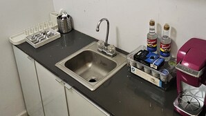 Een keuken met een spoelbak, aanrecht en opbergplanken.