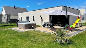 A modern house with a patio area, a hot tub, outdoor furniture, and a children's slide. - Gîte Luna villa 6 persons with jacuzzi, children's playground and petanque area (Chaumont-sur-Loire)
