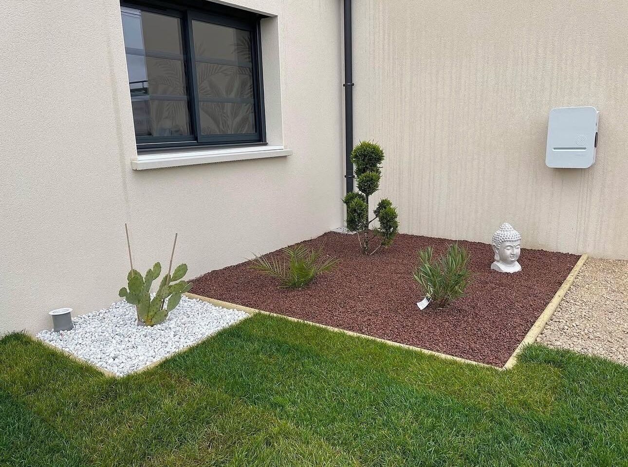 Jardim ajardinado com cactos, estátua de Buda e uma pequena árvore.