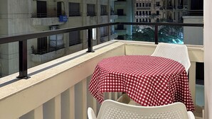 A balcony with a table and chairs, overlooking a building with multiple balconies and windows. - Imperial Hotel (Cairo)