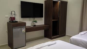Quarto de hotel com uma cama, uma escrivaninha com televisão, um minibar e um guarda-roupa.