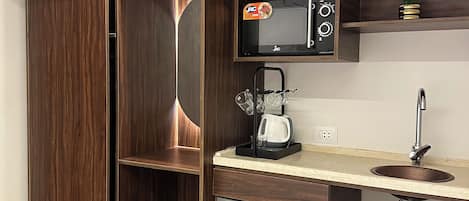 A compact kitchen with a built-in microwave, a coffee maker, and a small refrigerator.