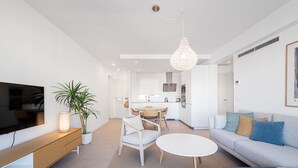 Ein modernes Wohnzimmer mit Fernseher, Sofa, Esstisch und Stühlen.