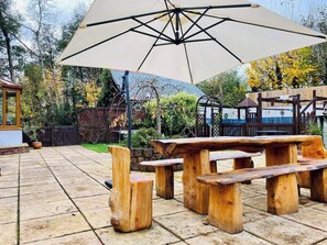 An outdoor patio with wooden benches and a large umbrella. - 5-bed Home - Sleeps 12, Pool, Garden & Play Area (Taunton)