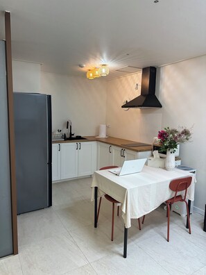 A modern kitchen with white cabinets, a black range hood, and a dining area with a table and chairs.