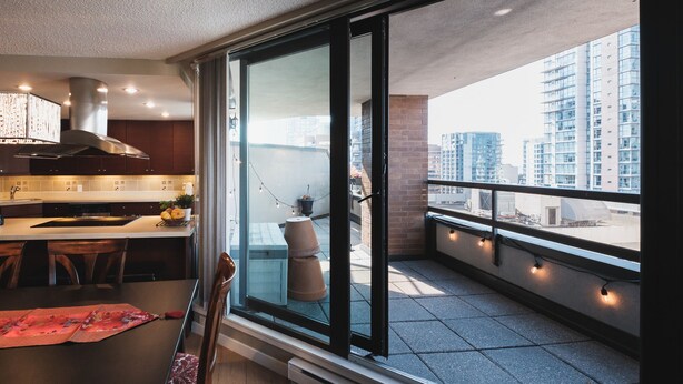 A modern kitchen with a large island, a dining area with a table and chairs, and a balcony with a city view. - Spacious and comfortable newly updated penthouse condo in downtown Vancouver (Vancouver)
