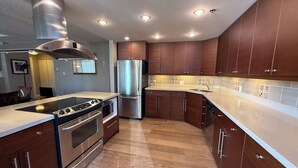 A modern kitchen with stainless steel appliances, wooden cabinets, and a herringbone floor pattern. - Spacious and comfortable newly updated penthouse condo in downtown Vancouver (Vancouver)