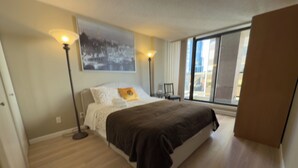 A modern bedroom with a large bed, a nightstand, a floor lamp, and a window with a view of the city. - Spacious and comfortable newly updated penthouse condo in downtown Vancouver (Vancouver)