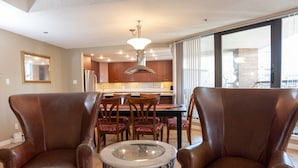 A dining area with two leather chairs, a glass-top table, and a kitchen in the background. - Spacious and comfortable newly updated penthouse condo in downtown Vancouver (Vancouver)