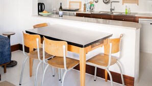 A modern kitchen with a central island, wooden chairs, and a white dining table. - 2-BR House with garden in fishing village Ferragudo, by the river and the ocean. (Ferragudo)