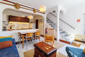 A modern interior with a kitchen, dining area, and staircase.