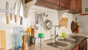 A kitchen with wooden cabinets, a stainless steel sink, hanging knives, and various kitchen utensils. - 2-BR House with garden in fishing village Ferragudo, by the river and the ocean. (Ferragudo)