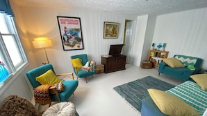 A cozy living room with teal armchairs, a blue sofa, and a patterned rug.