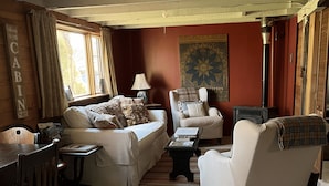 A cozy living room with a sofa, armchairs, a wooden table, and a fireplace. - Dream Cabin in charming Hyde Park with WiFi access (HYDE PARK)